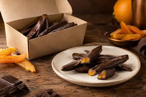 Orangettes à l’écorce d’orange confite enrobées de chocolat noir, présentées dans un ballotin ouvert
